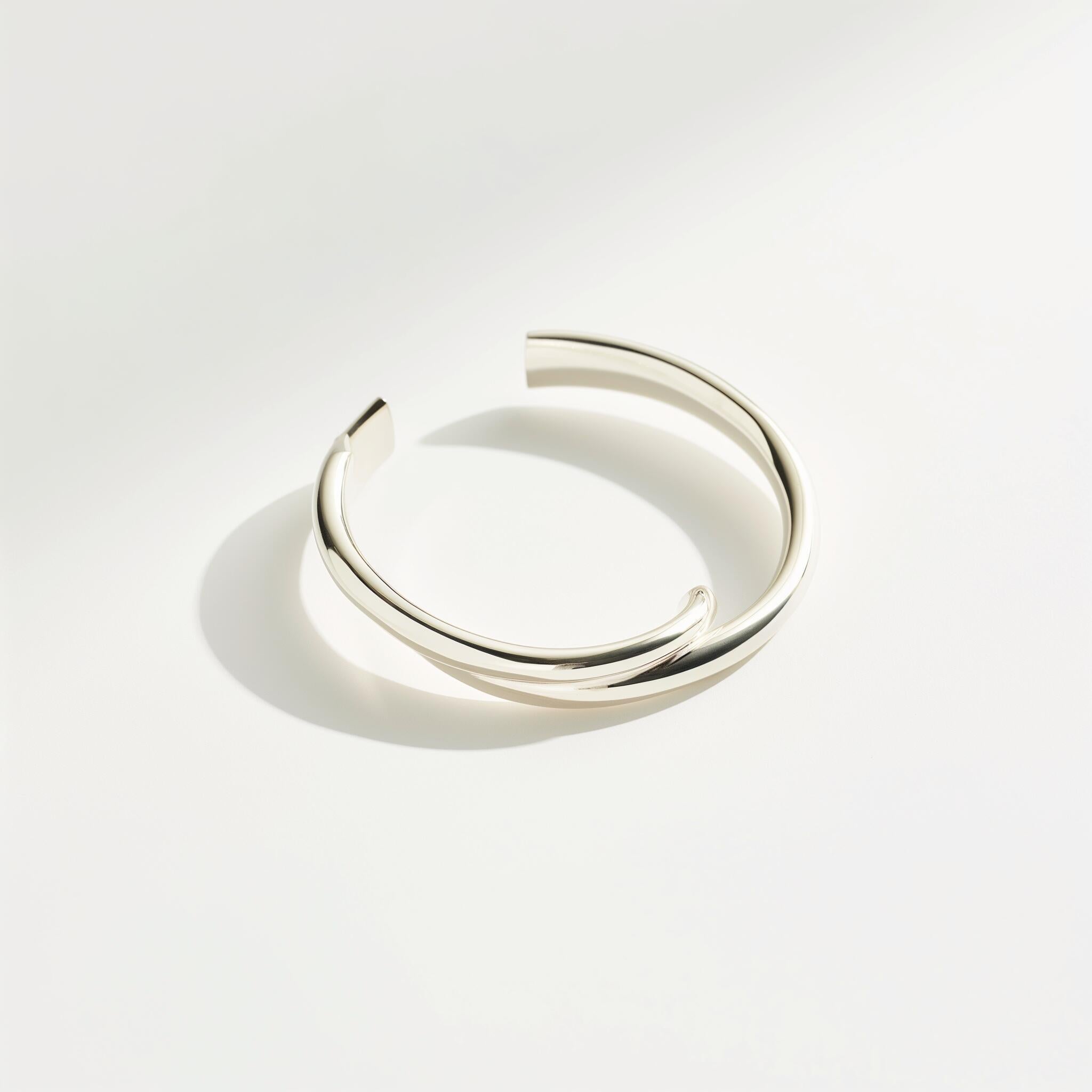 Minimalist open cuff bracelet with a polished silver-tone finish on a white background