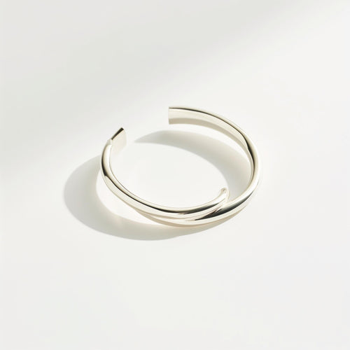 Minimalist open cuff bracelet with a polished silver-tone finish on a white background